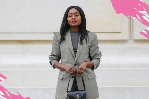 Eine Frau im karierten Blazer und schwarzer Tasche zeigt, was ist business casual: schick und doch entspannt.
