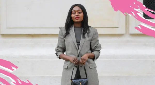 Eine Frau im karierten Blazer und schwarzer Tasche zeigt, was ist business casual: schick und doch entspannt.